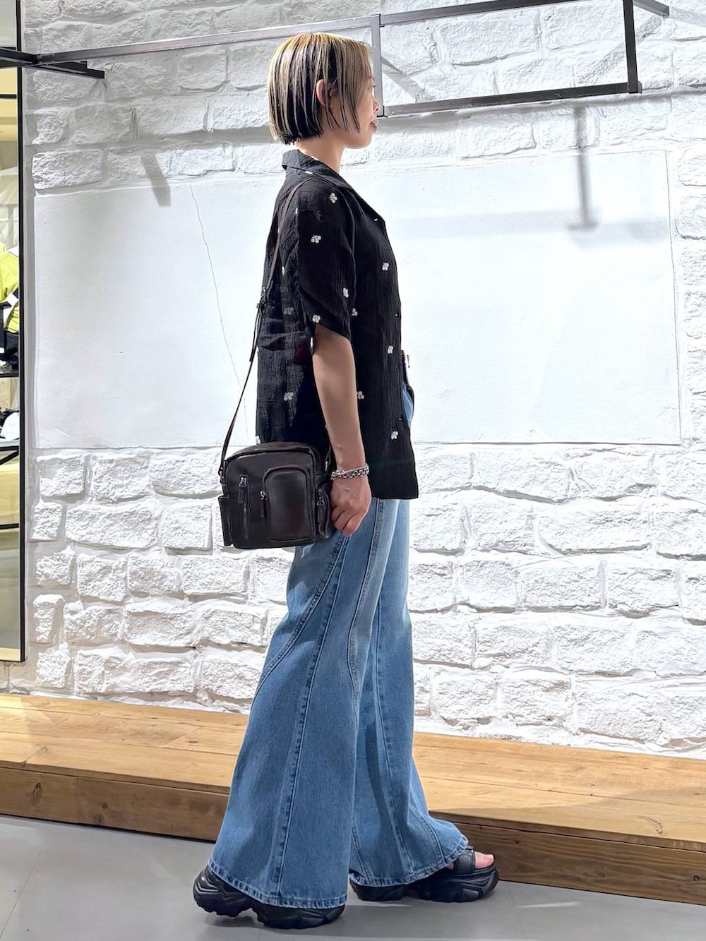ブルー系のデニムパンツ、ブラウン系のショルダーバッグ、ブラック系のサンダルを着用したレディースの春コーディネートの4枚目の写真