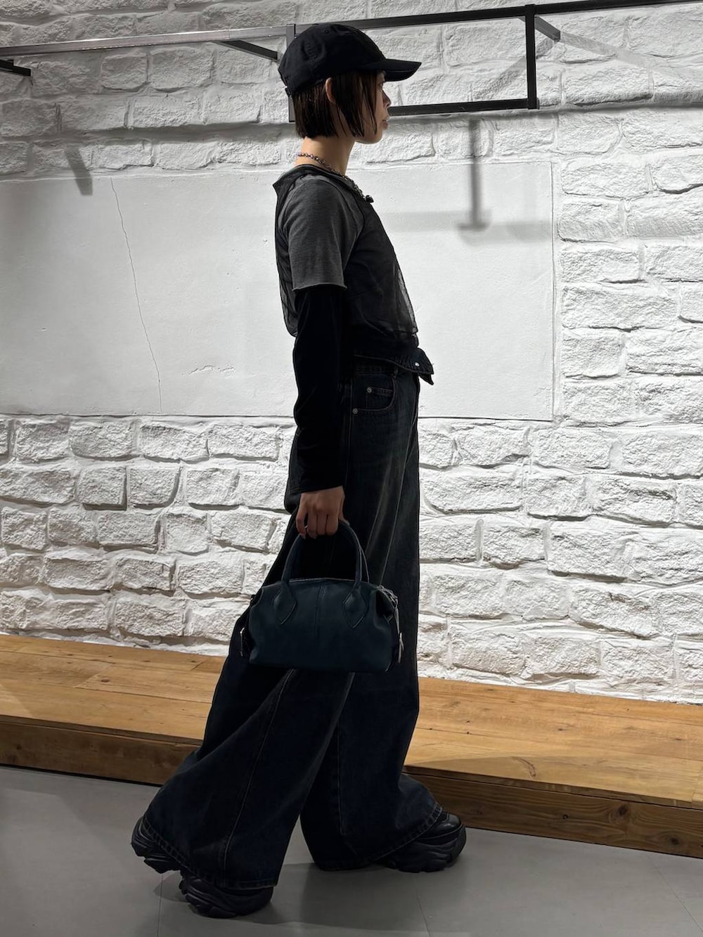 ブラック系のスニーカー、ブルー系のデニムパンツ、ブルー系のショルダーバッグを着用したレディースの秋コーディネートの4枚目の写真