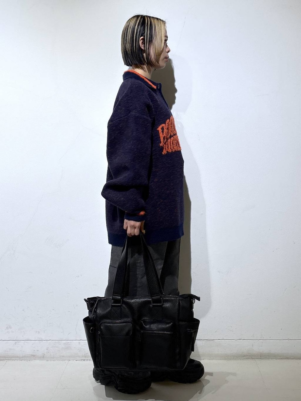 ブラック系のブーツ、ブラック系のボストンバッグ、ブルー系のニット/セーターを着用したレディースの秋コーディネートの3枚目の写真