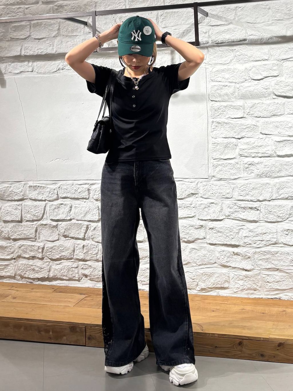 ブラック系のデニムパンツ、ブラック系のTシャツ/カットソー、ホワイト系のスニーカーを着用したレディースの夏コーディネートの2枚目の写真