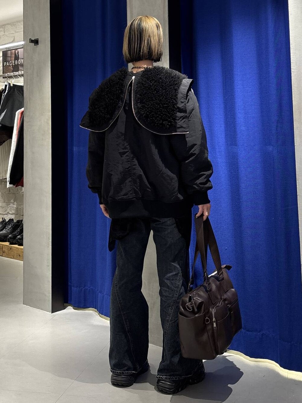 ブラック系のスニーカー、ブルー系のデニムパンツ、ブラウン系のボストンバッグを着用したレディースの冬コーディネートの4枚目の写真