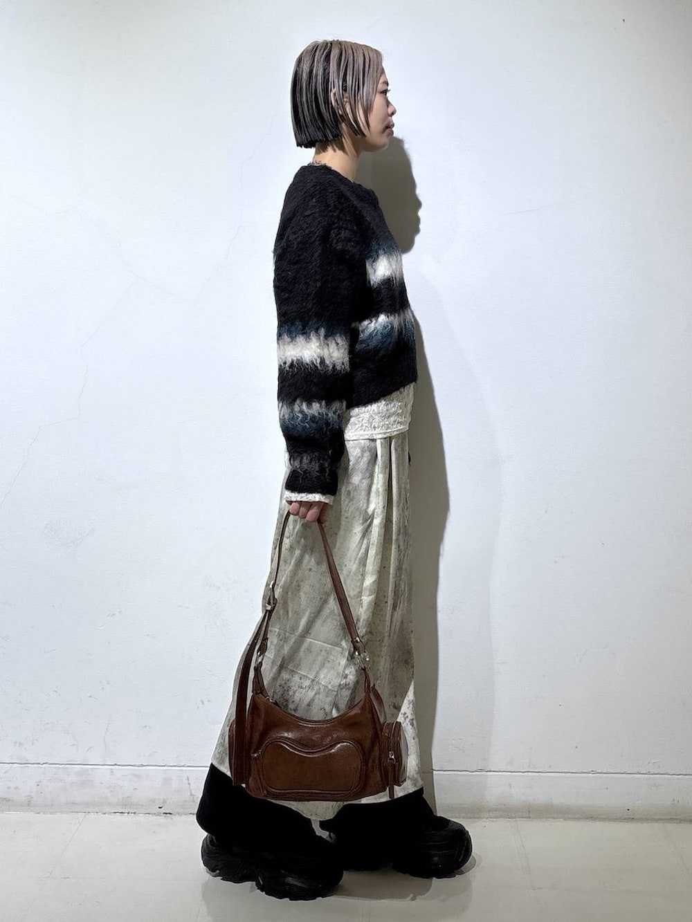 ブラック系のブーツ、ホワイト系のTシャツ/カットソー、ブラウン系のショルダーバッグを着用したレディースの冬コーディネートの3枚目の写真