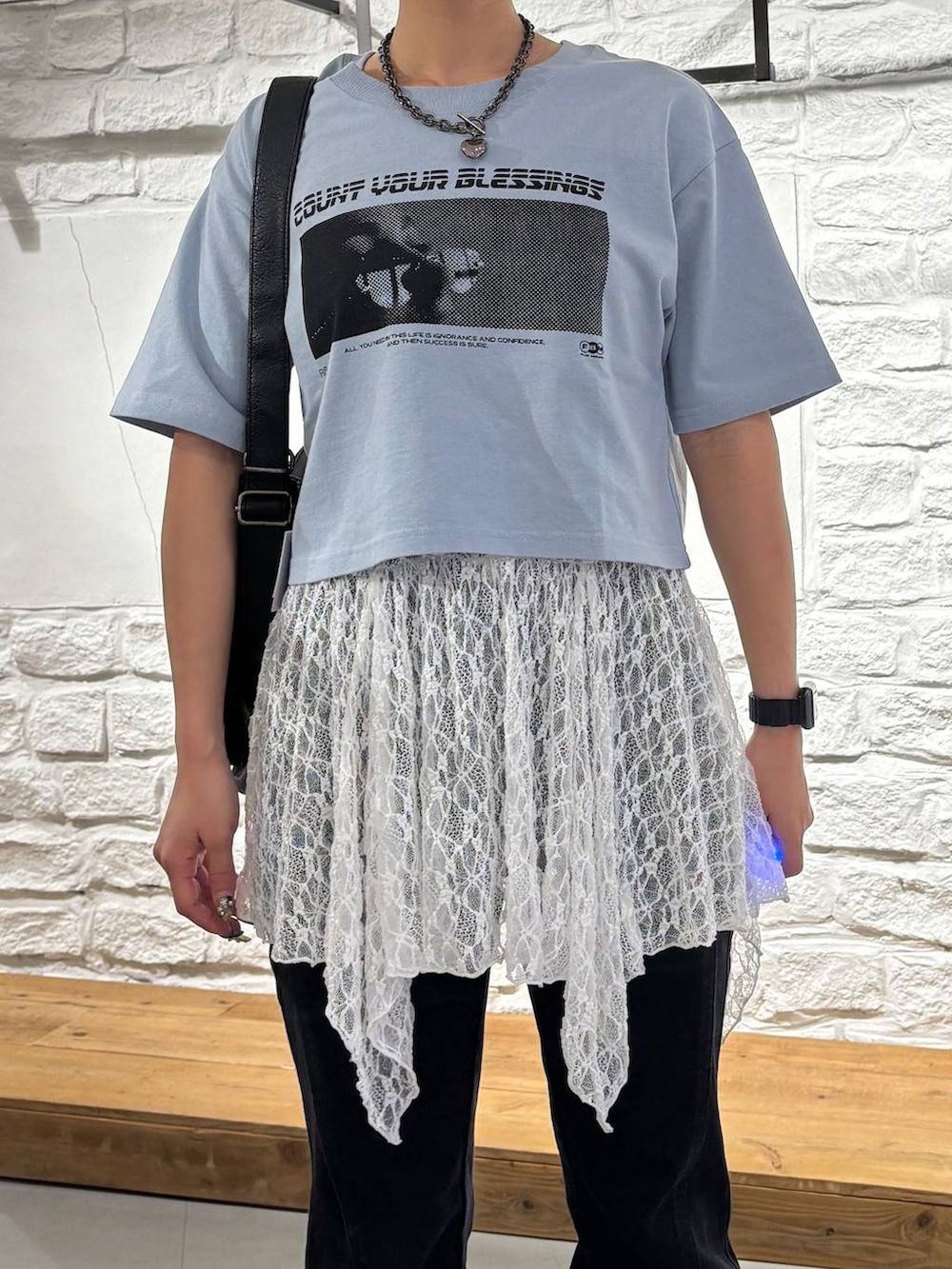 ブルー系のTシャツ/カットソー、ブラック系のデニムパンツ、ブラック系のショルダーバッグを着用したレディースの夏コーディネートの4枚目の写真