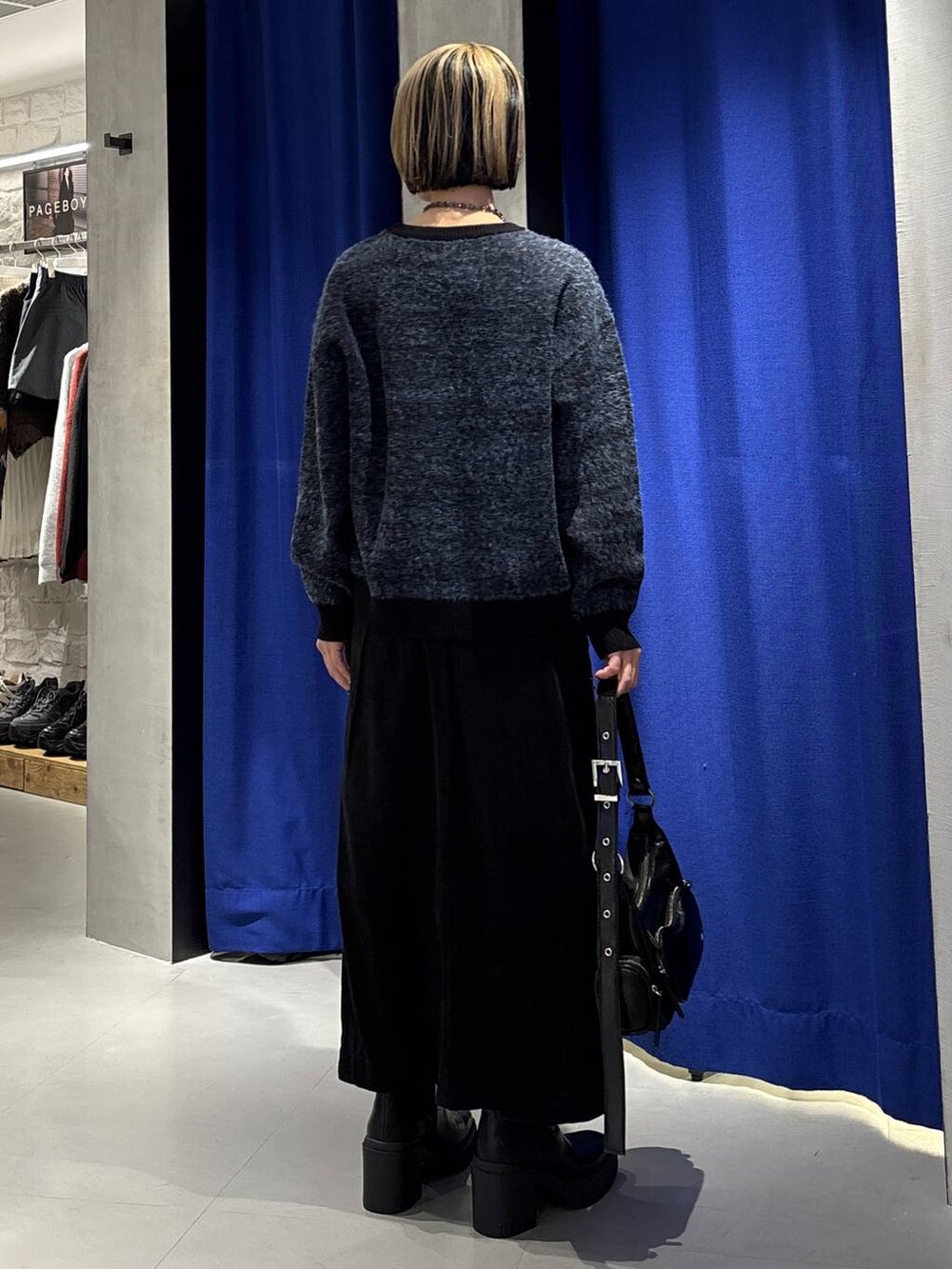 ブラック系のブーツ、ブラック系のショルダーバッグ、ブラック系のスカートを着用したレディースの冬コーディネートの4枚目の写真