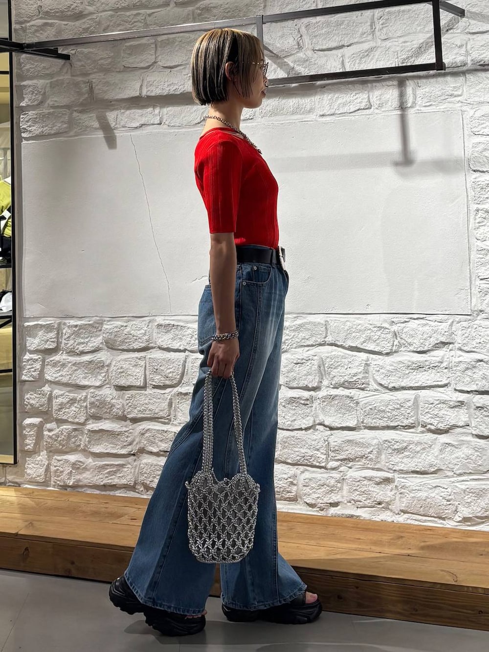 ブルー系のデニムパンツ、ブラック系のサンダル、レッド系のニット/セーターを着用したレディースの春コーディネートの4枚目の写真
