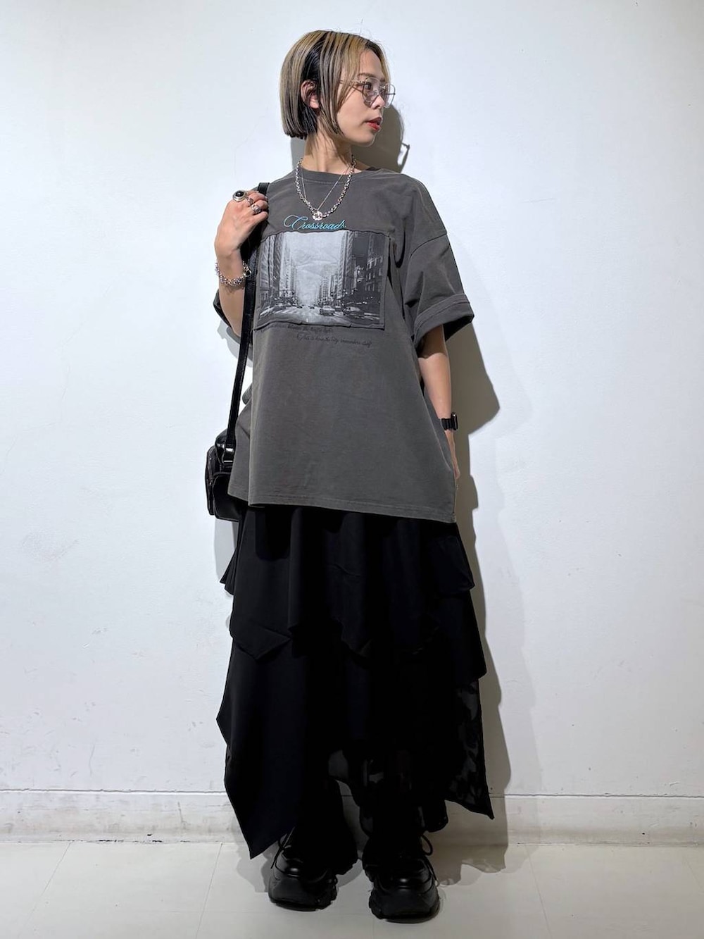 ブラック系のスニーカー、ブラック系のショルダーバッグ、グレー系のTシャツ/カットソーを着用したレディースの夏コーディネートの2枚目の写真