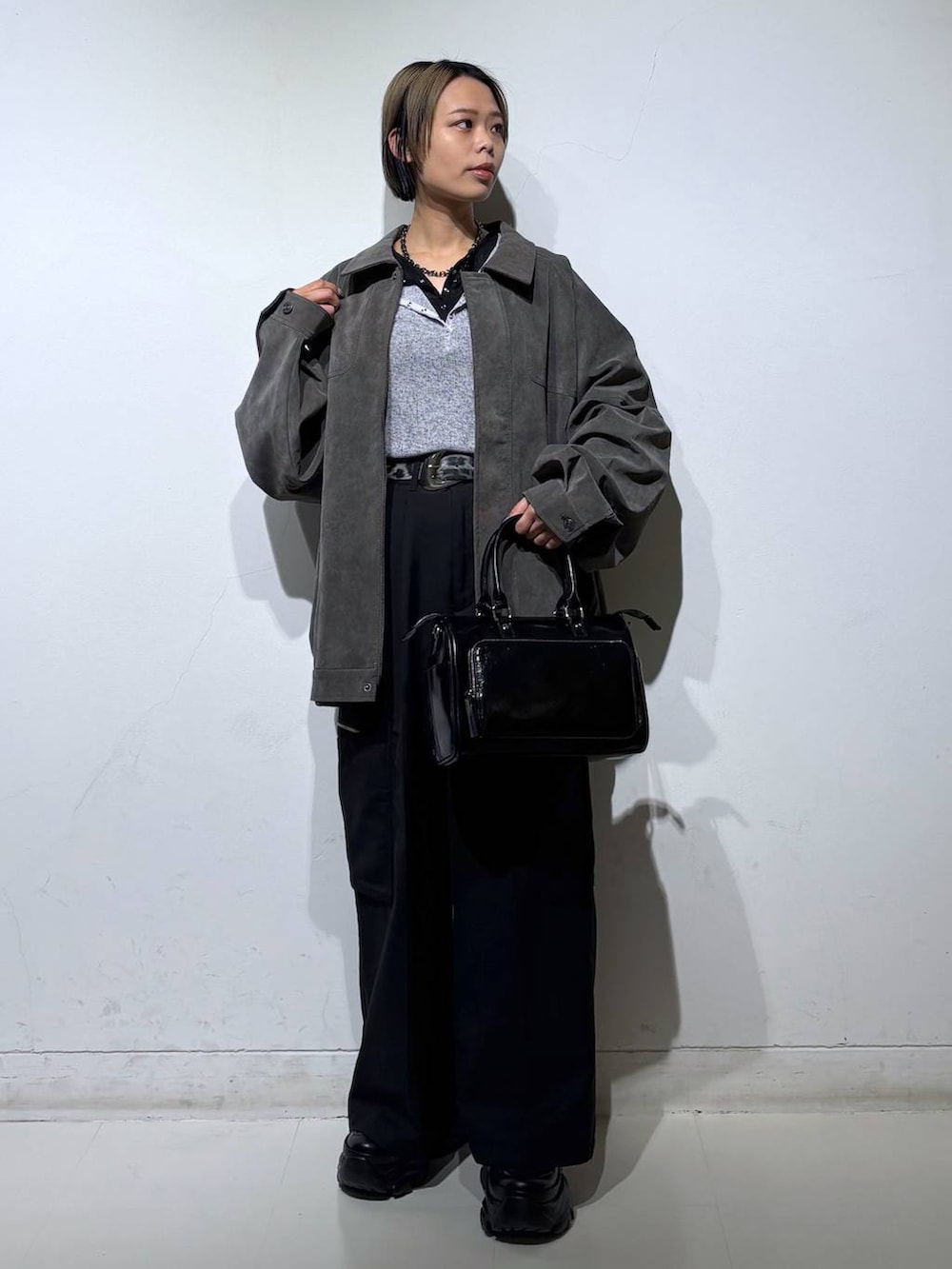 ブラック系のスニーカー、ブラック系のショルダーバッグ、グレー系のブルゾンを着用したレディースの春コーディネートの2枚目の写真