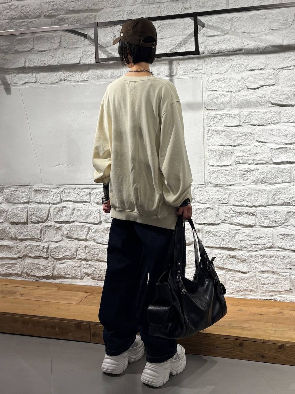 ブルー系のデニムパンツ、ホワイト系のスニーカー、ブラック系のトートバッグを着用したレディースの秋コーディネートの6枚目の写真