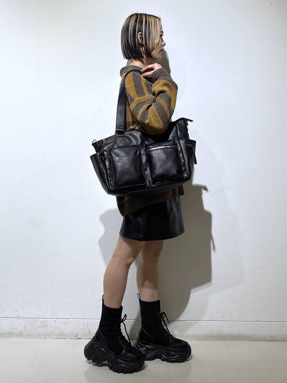 ブラック系のブーツ、ブラック系のボストンバッグ、ブラック系のスカートを着用したレディースの冬コーディネートの3枚目の写真