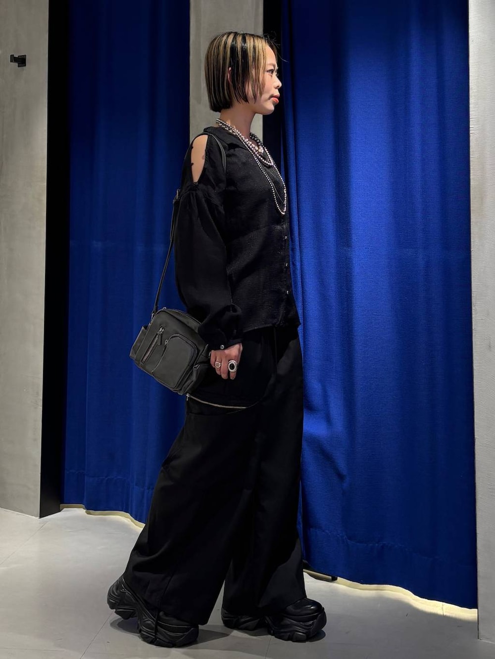 ブラック系のスニーカー、ブラック系のスラックス、グレー系のショルダーバッグを着用したレディースの春コーディネートの3枚目の写真