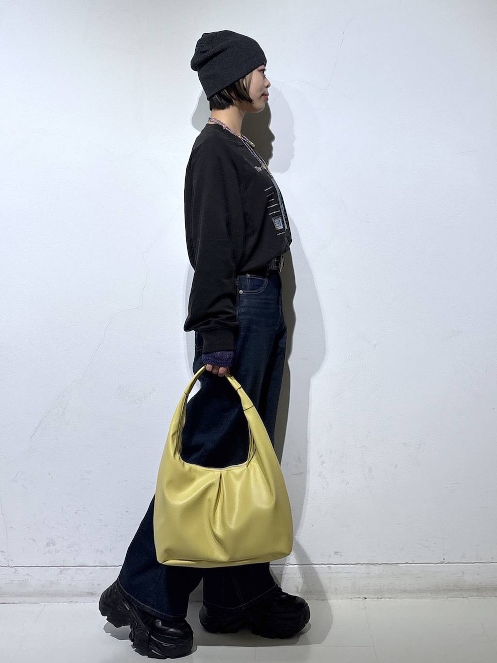 ブラック系のスニーカー、ブルー系のスラックス、イエロー系のトートバッグを着用したレディースの春コーディネートの4枚目の写真