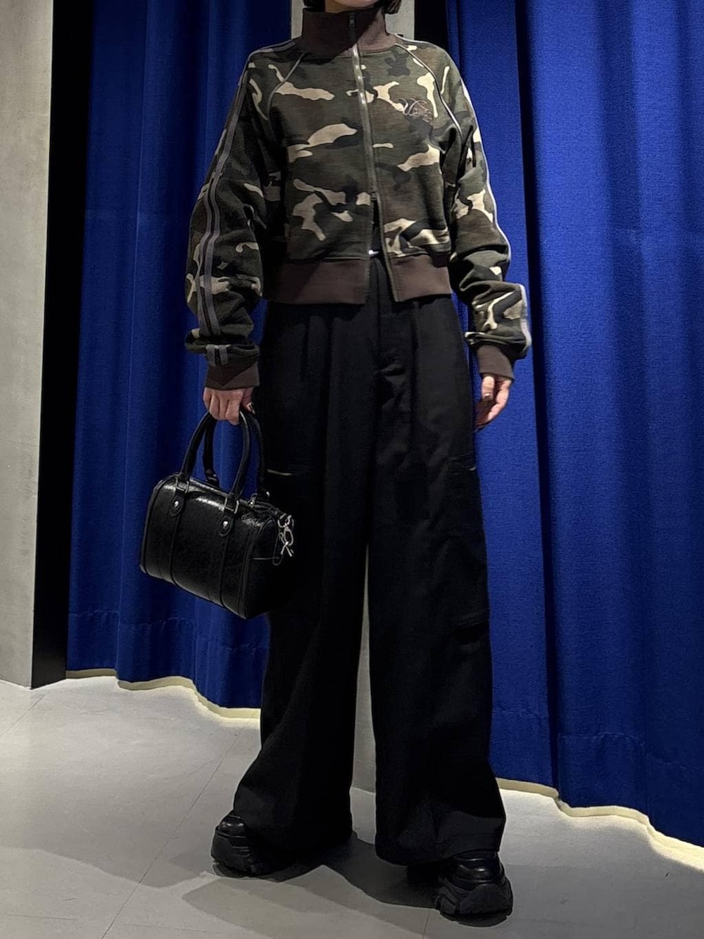 ブラック系のスニーカー、ブラック系のボストンバッグ、ブラック系のスラックスを着用したレディースの冬コーディネートの2枚目の写真