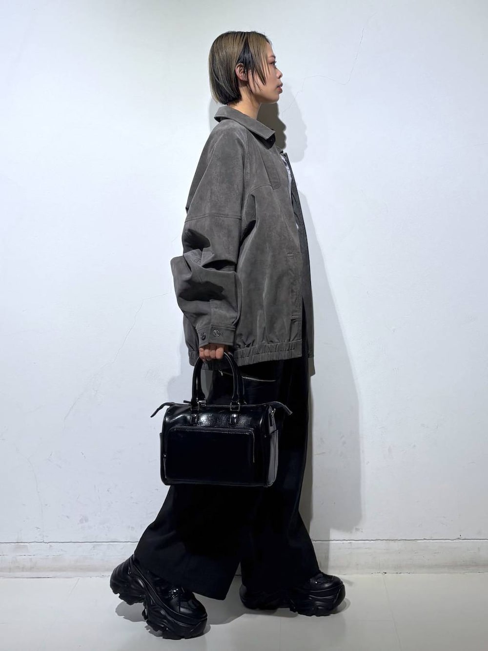 ブラック系のスニーカー、ブラック系のショルダーバッグ、グレー系のブルゾンを着用したレディースの春コーディネートの4枚目の写真