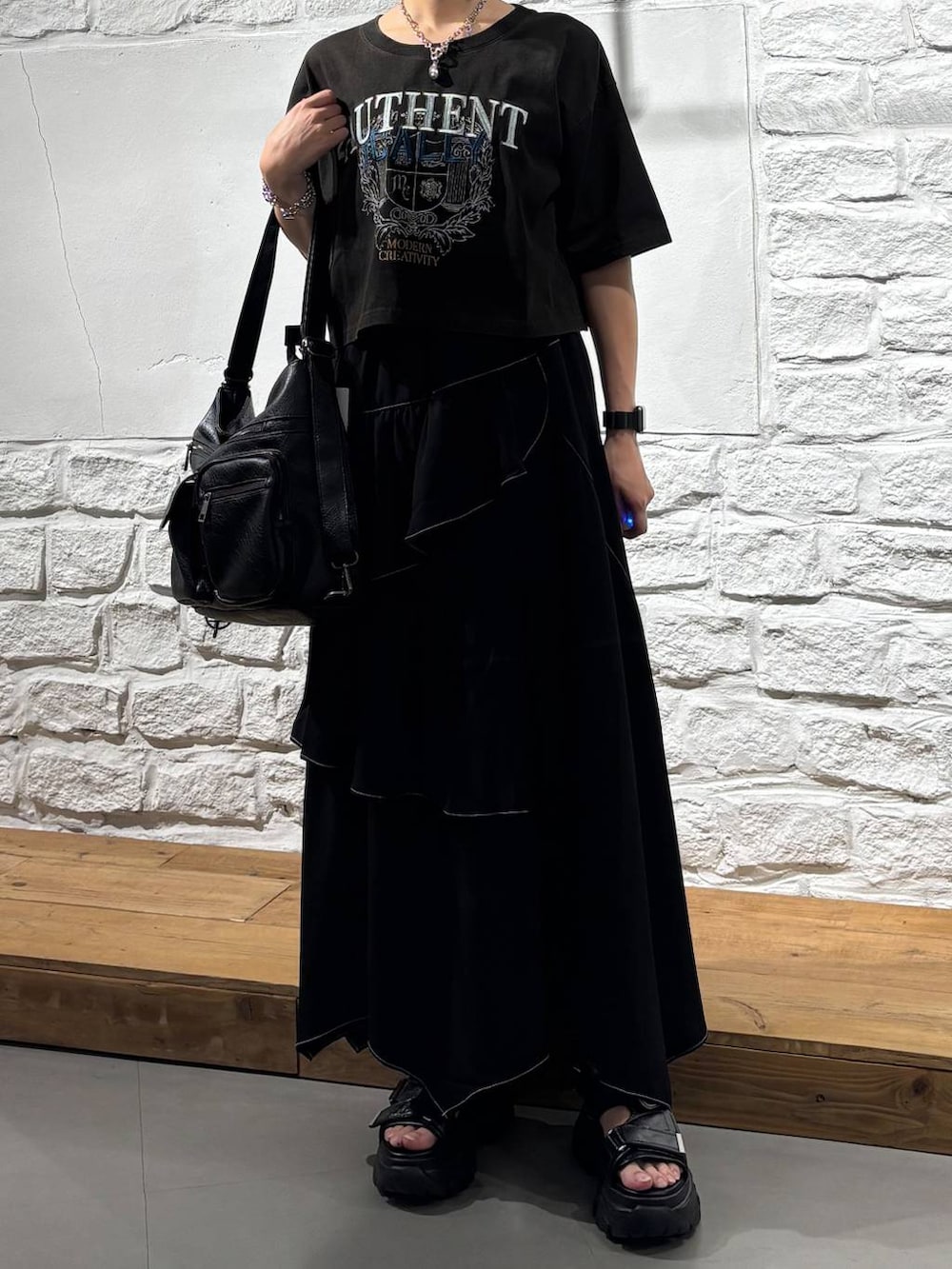 ブラック系のスカート、グレー系のTシャツ/カットソー、ブラック系のショルダーバッグを着用したレディースの夏コーディネートの3枚目の写真
