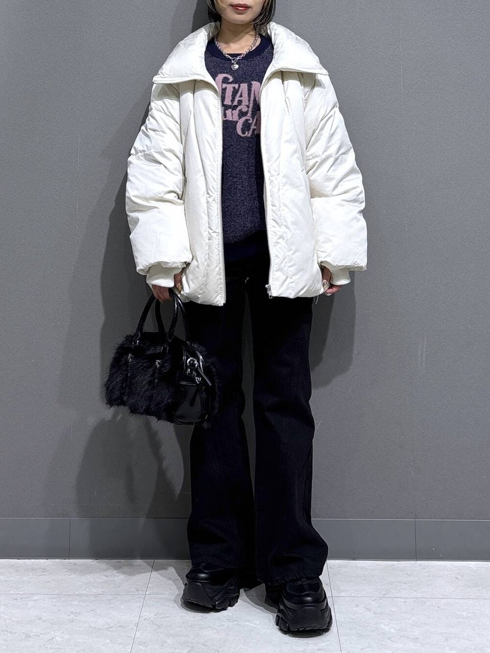 ブラック系のブーツ、ブラック系のデニムパンツ、ホワイト系のブルゾンを着用したレディースの冬コーディネートの2枚目の写真