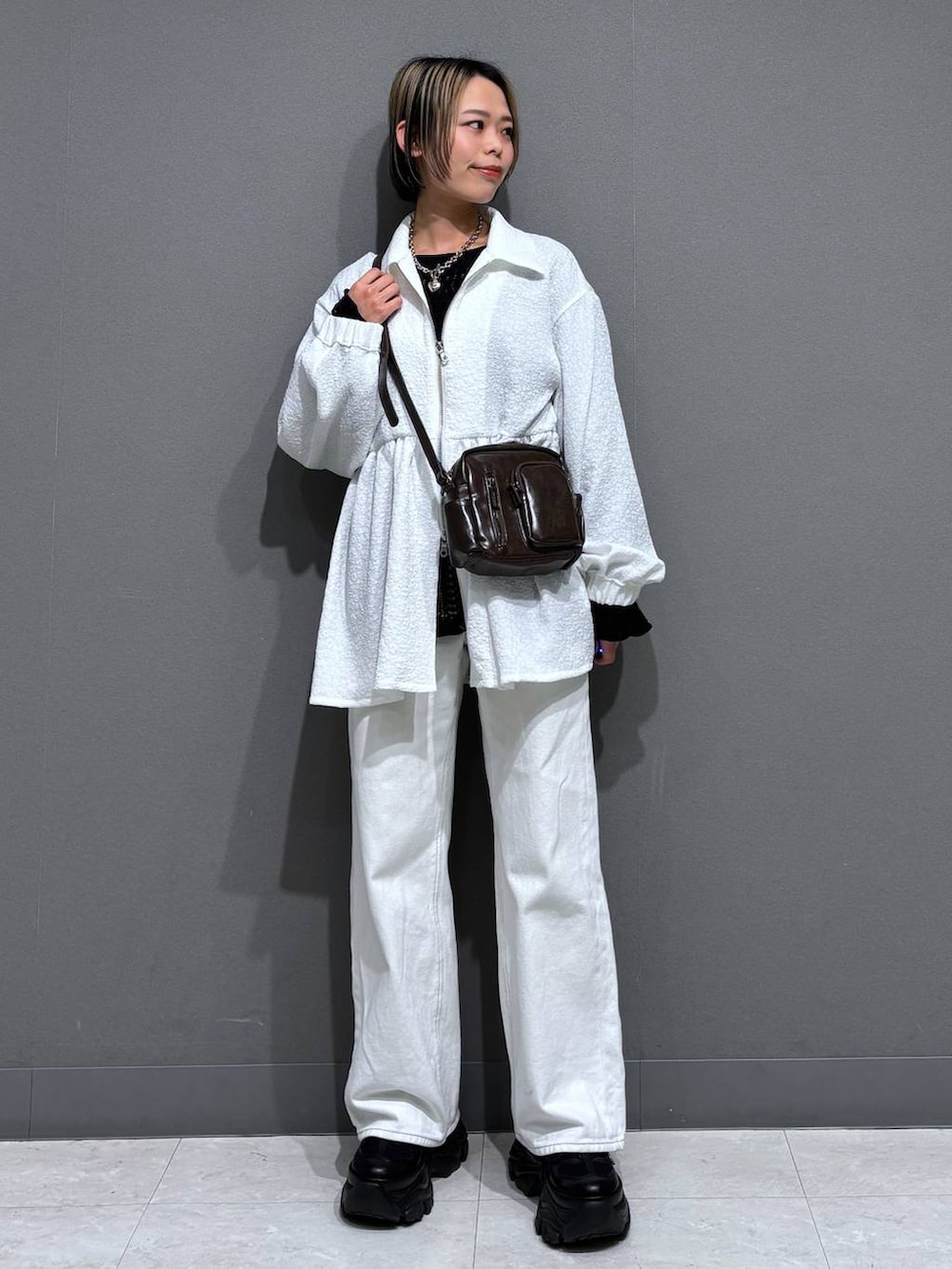 ブラック系のスニーカー、ホワイト系のスラックス、ブラウン系のショルダーバッグを着用したレディースの春コーディネートの2枚目の写真