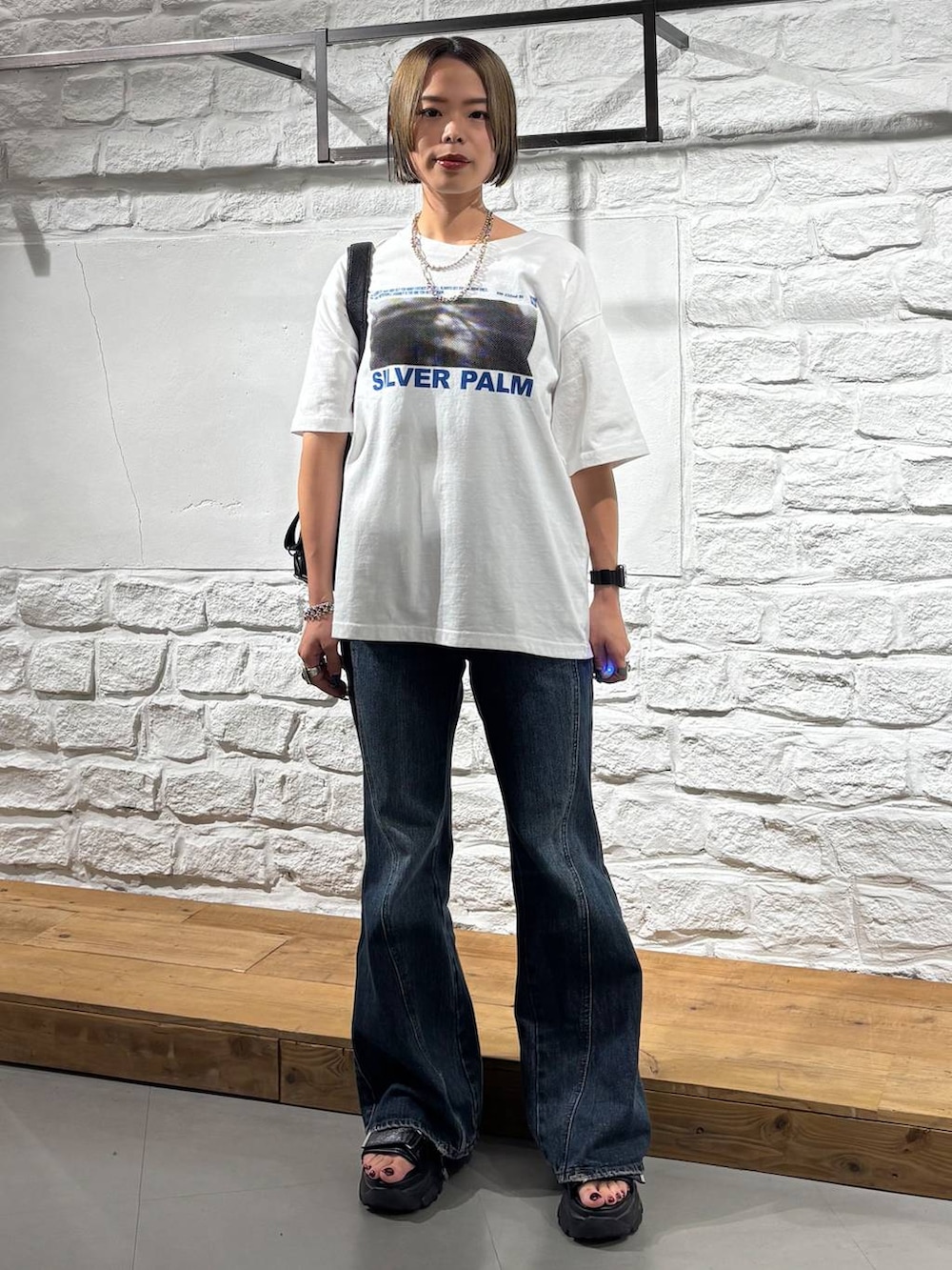 ホワイト系のTシャツ/カットソー、ブルー系のデニムパンツ、ブラック系のショルダーバッグを着用したレディースの夏コーディネートの2枚目の写真