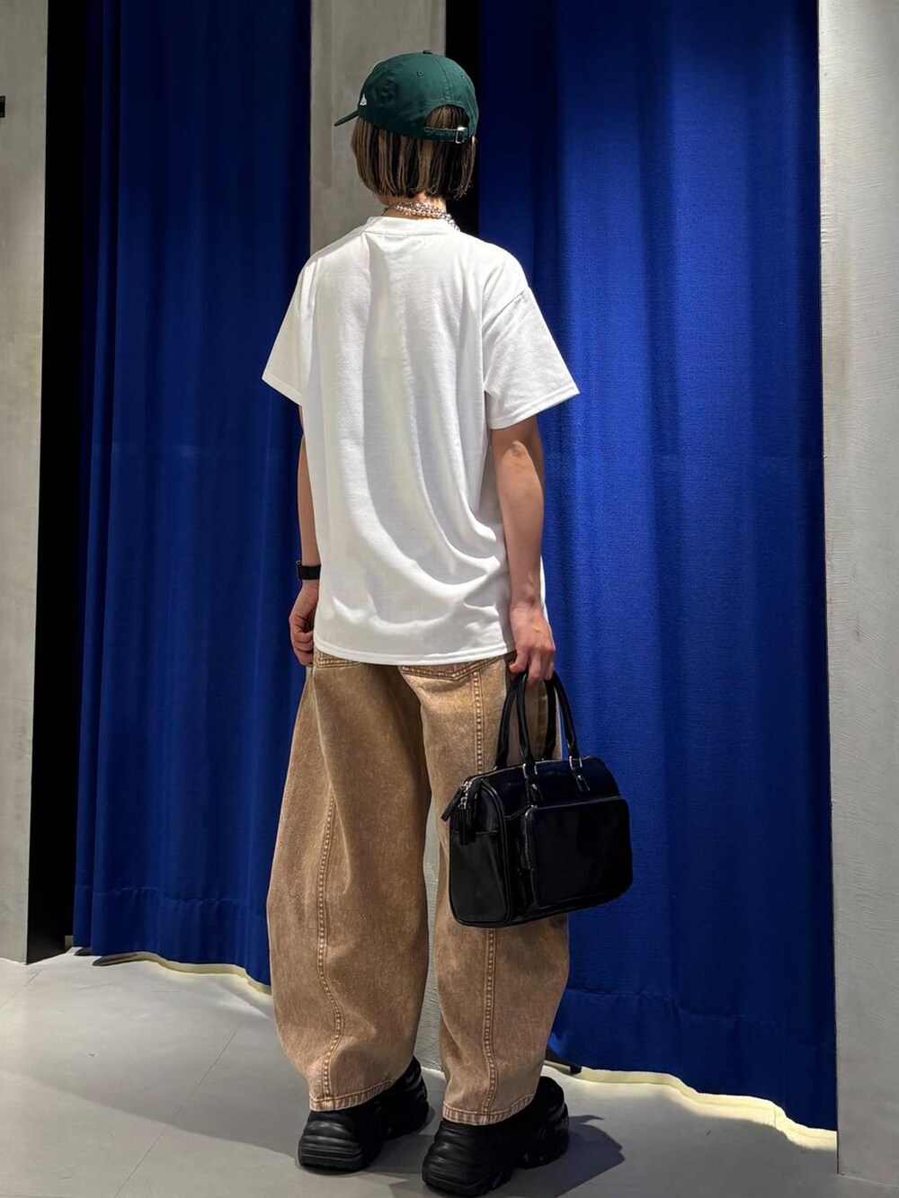 ブラック系のスニーカー、ブラウン系のデニムパンツ、ブラック系のショルダーバッグを着用したレディースの春コーディネートの6枚目の写真