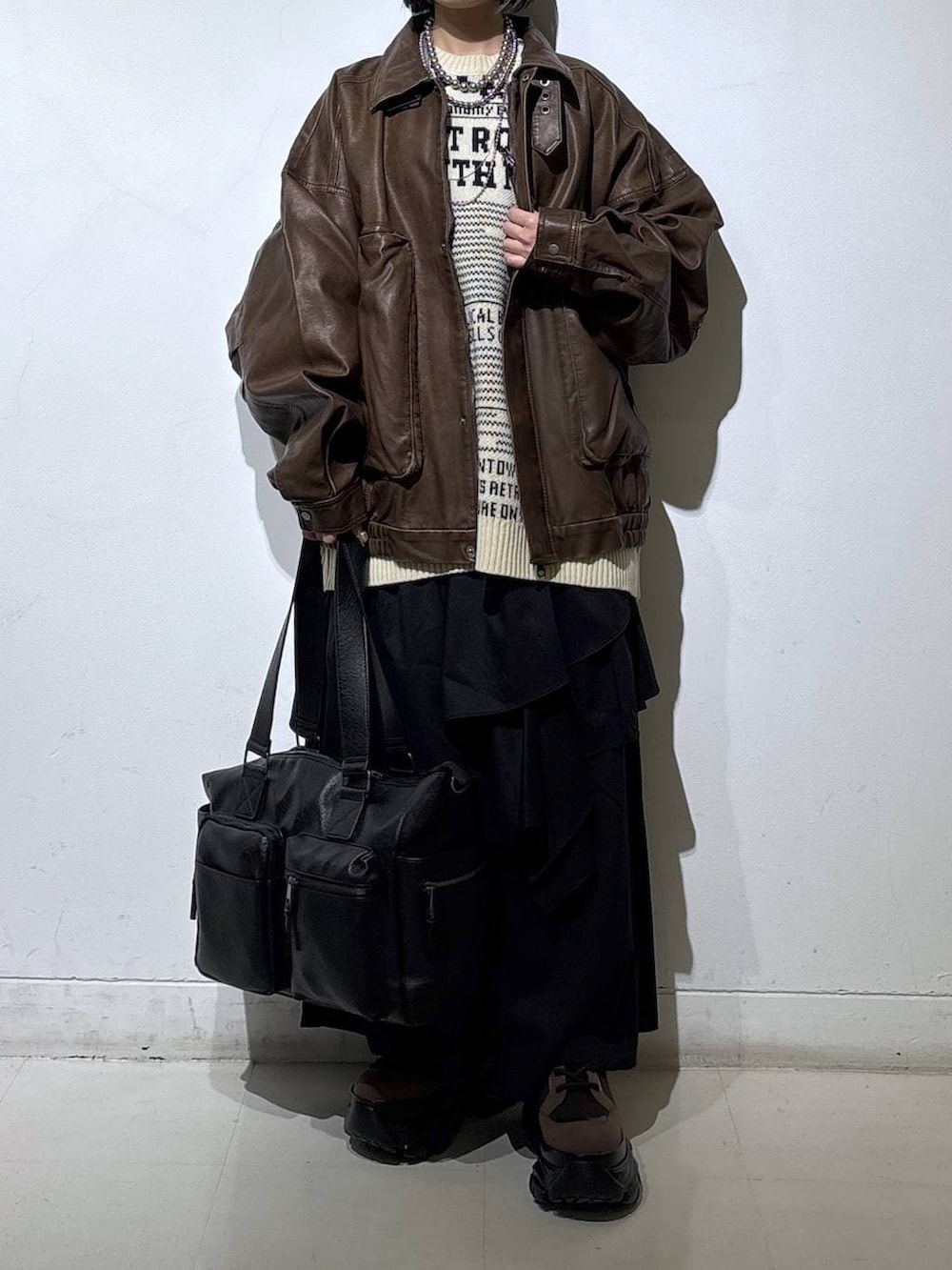 ブラウン系のブーツ、ブラック系のボストンバッグ、ブラック系のスカートを着用したレディースの冬コーディネートの2枚目の写真