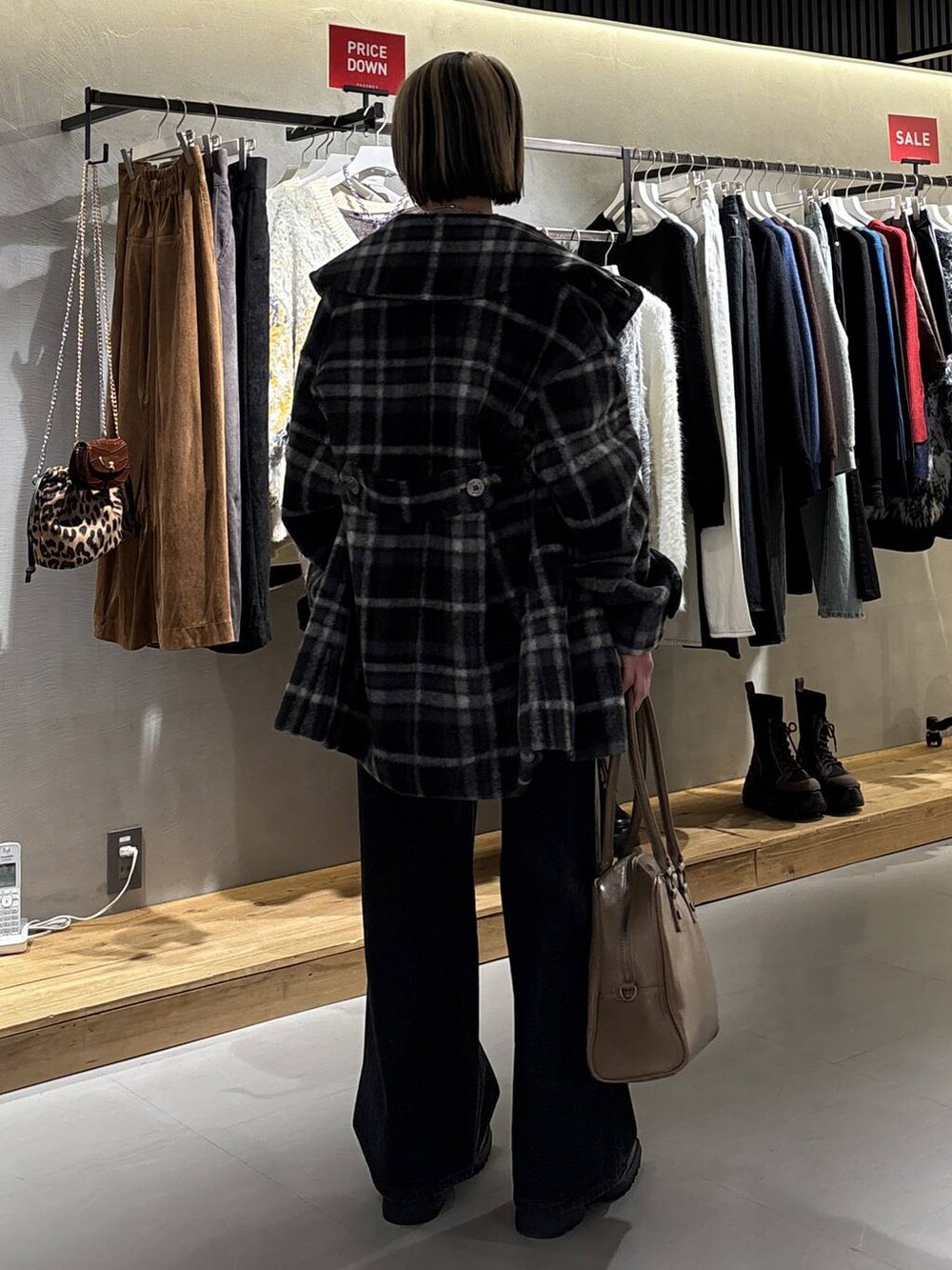 ベージュ系のボストンバッグ、ブラック系のデニムパンツ、ブラック系のチェスターコートを着用したレディースの冬コーディネートの5枚目の写真