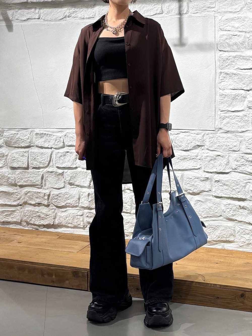 ブラック系のスニーカー、ブラック系のデニムパンツ、ブルー系のハンドバッグを着用したレディースの春コーディネートの3枚目の写真