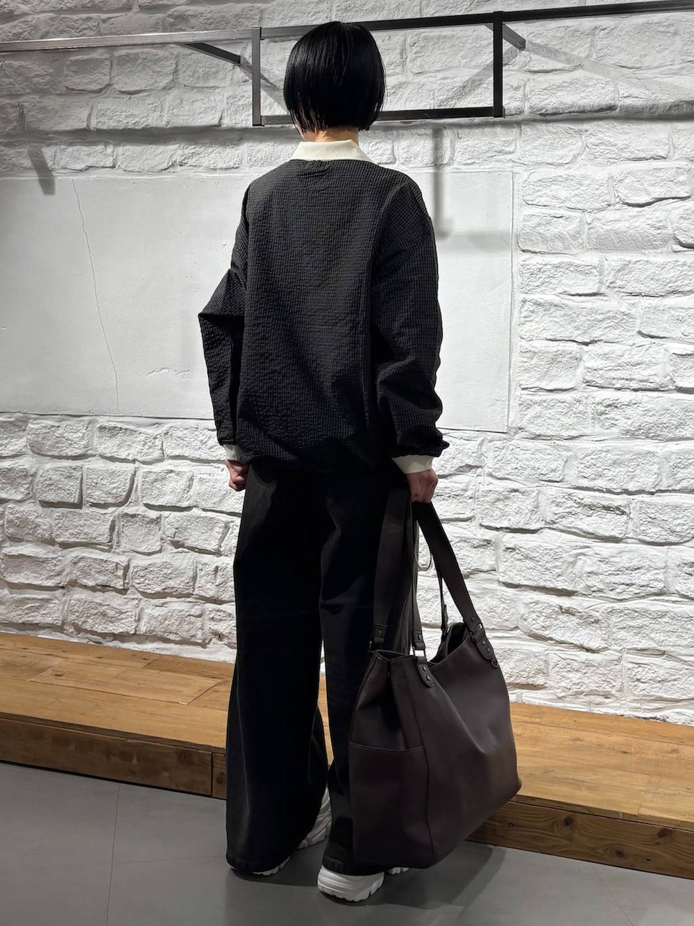 ホワイト系のスニーカー、ブラック系のデニムパンツ、ブラウン系のトートバッグを着用したレディースの秋コーディネートの4枚目の写真