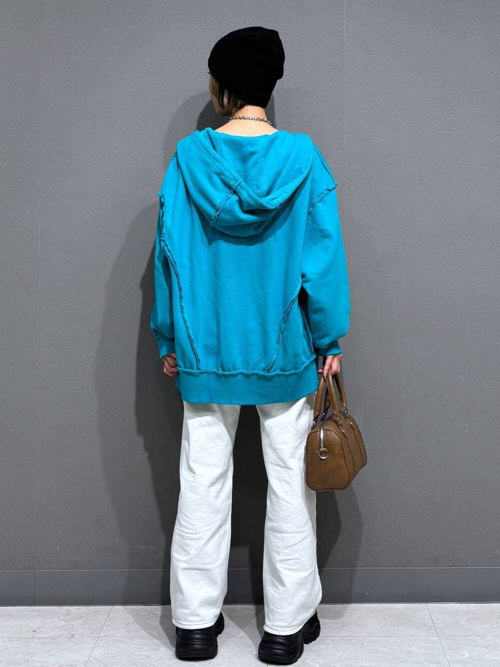 ブラック系のスニーカー、ホワイト系のスラックス、ブラウン系のボストンバッグを着用したレディースの春コーディネートの5枚目の写真