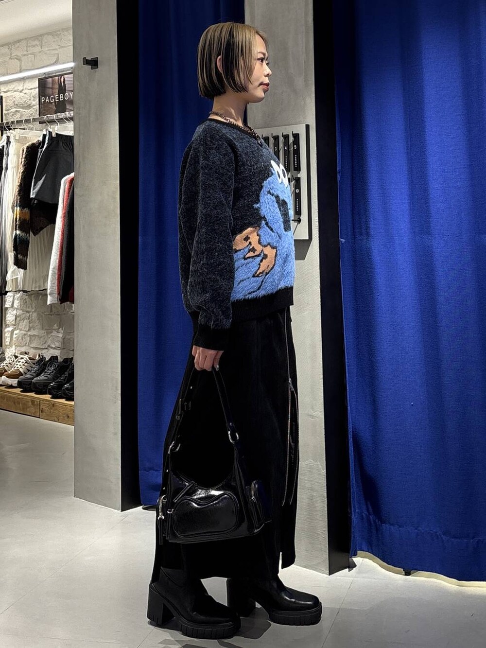 ブラック系のブーツ、ブラック系のショルダーバッグ、ブラック系のスカートを着用したレディースの冬コーディネートの3枚目の写真