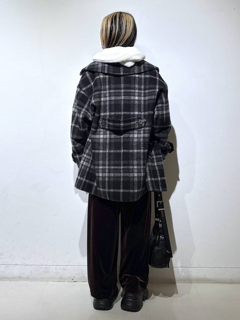 ブラック系のブーツ、ブラック系のチェスターコート、ホワイト系のパーカーを着用したレディースの秋コーディネートの4枚目の写真