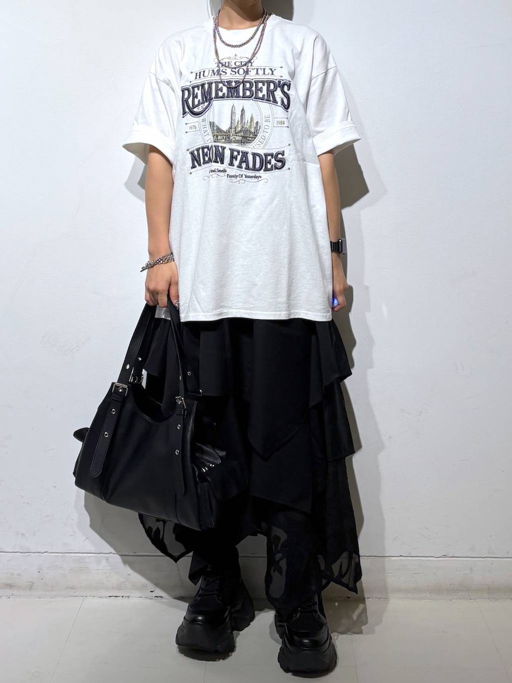 ブラック系のブーツ、ホワイト系のTシャツ/カットソー、ブラック系のハンドバッグを着用したレディースの夏コーディネートの3枚目の写真