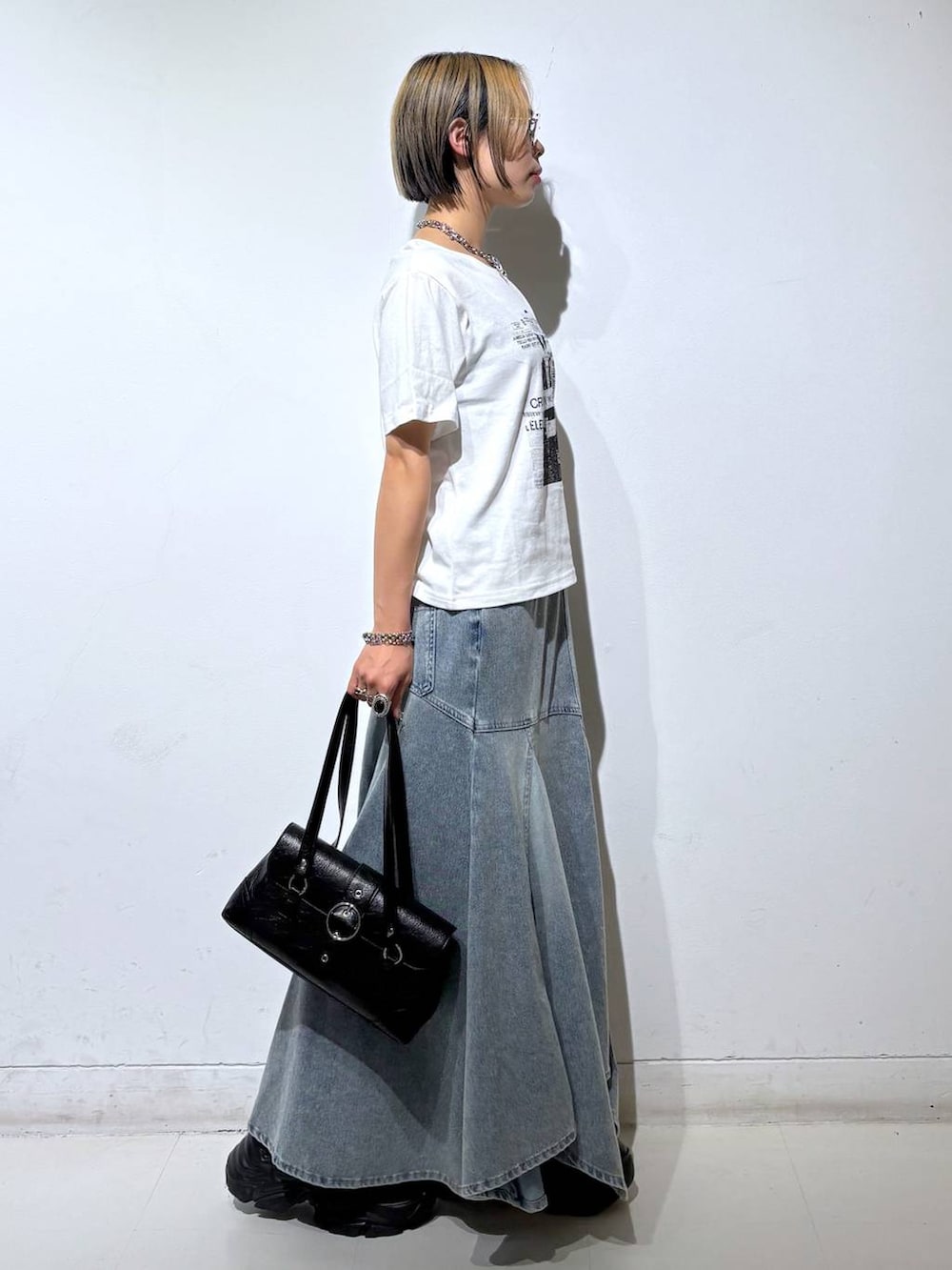 ホワイト系のTシャツ/カットソー、ブラック系のスニーカー、ブルー系のデニムスカートを着用したレディースの夏コーディネートの4枚目の写真