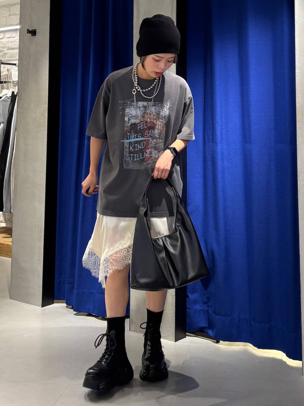 ブラック系のブーツ、ブラック系のトートバッグ、ホワイト系のチュニックを着用したレディースの春コーディネートの2枚目の写真