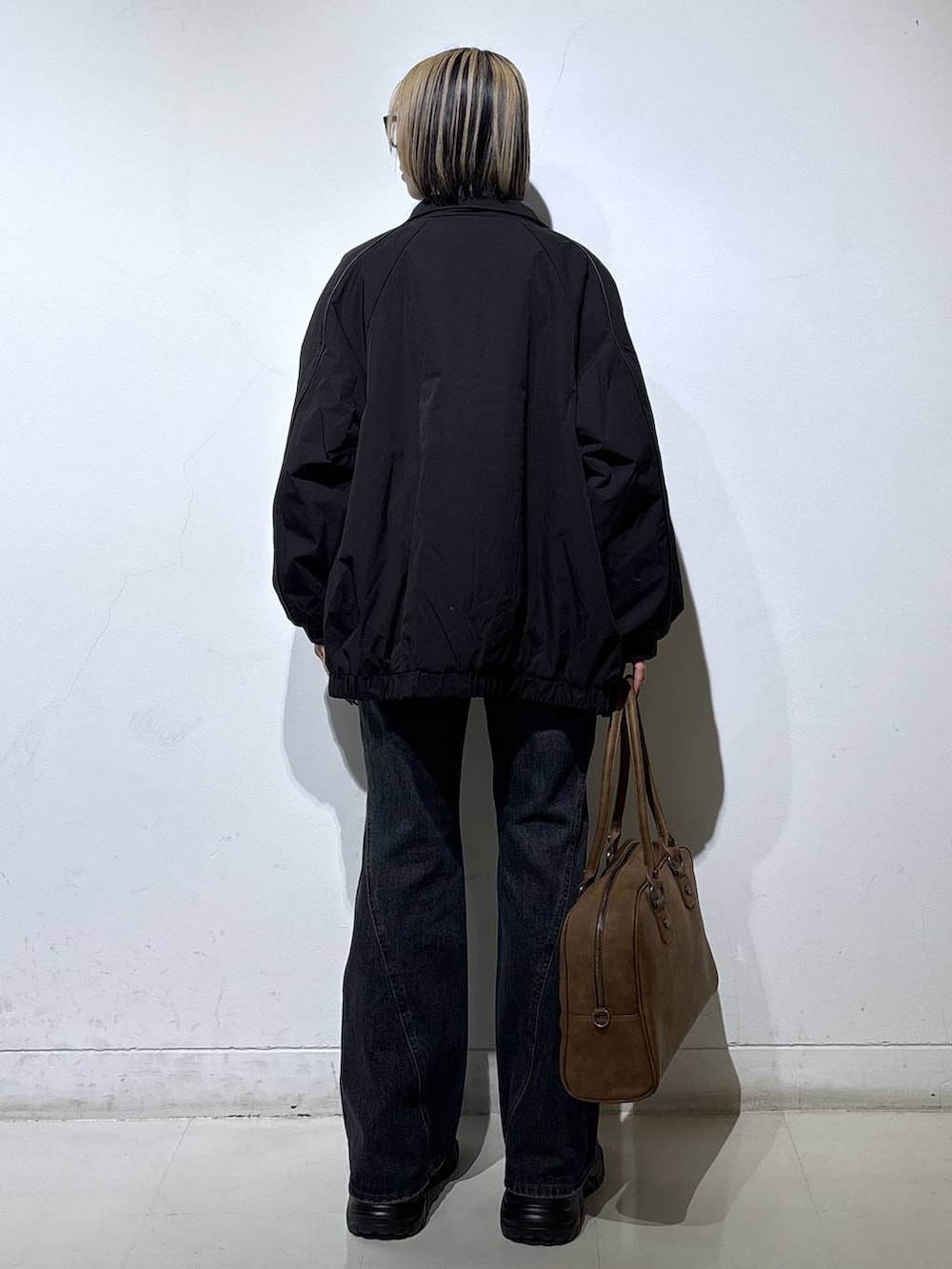 ブラック系のブーツ、ベージュ系のボストンバッグ、ブルー系のデニムパンツを着用したレディースの春コーディネートの4枚目の写真