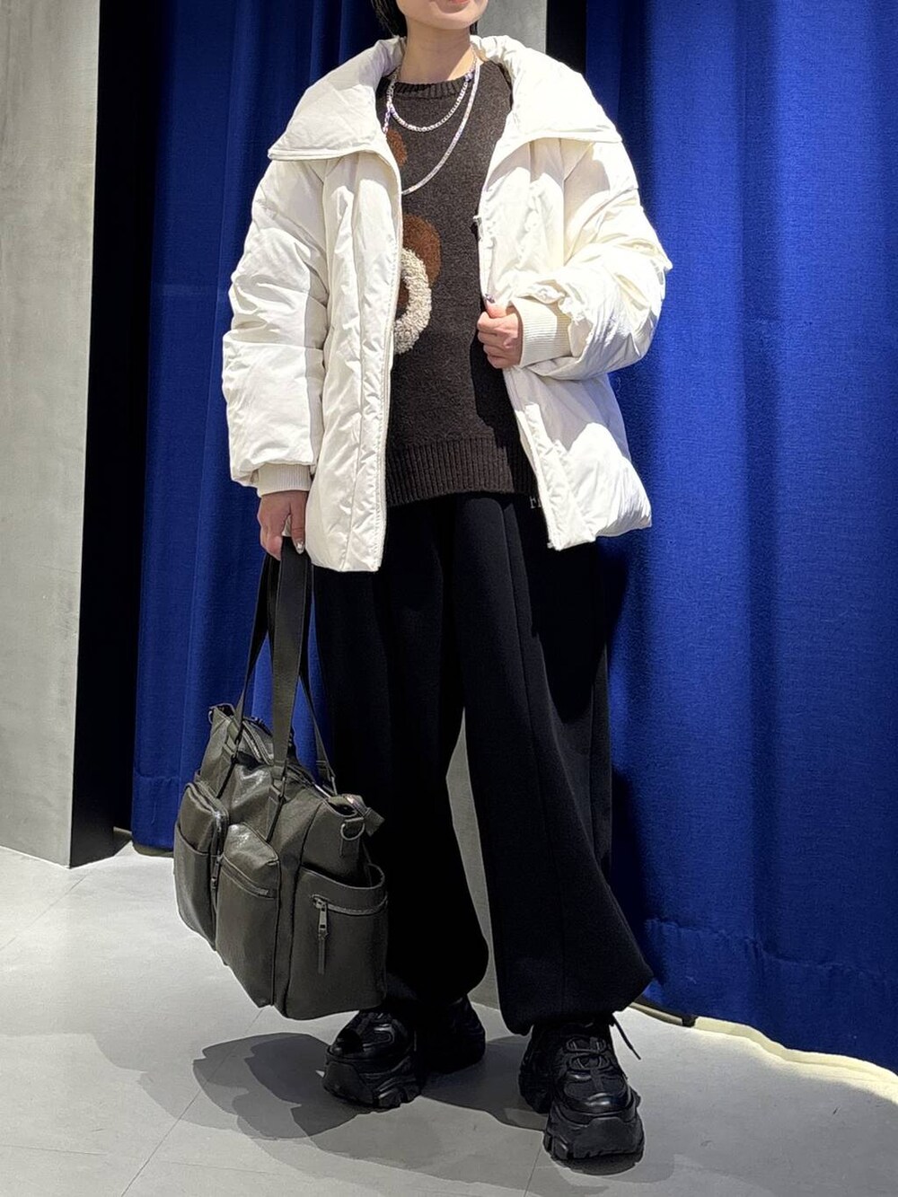 ブラック系のブーツ、グリーン系のボストンバッグ、ホワイト系のブルゾンを着用したレディースの冬コーディネートの2枚目の写真