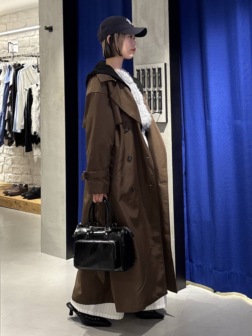 グレー系のニット/セーター、ブラウン系のトレンチコート、ブラック系のショルダーバッグを着用したレディースの冬コーディネートの4枚目の写真