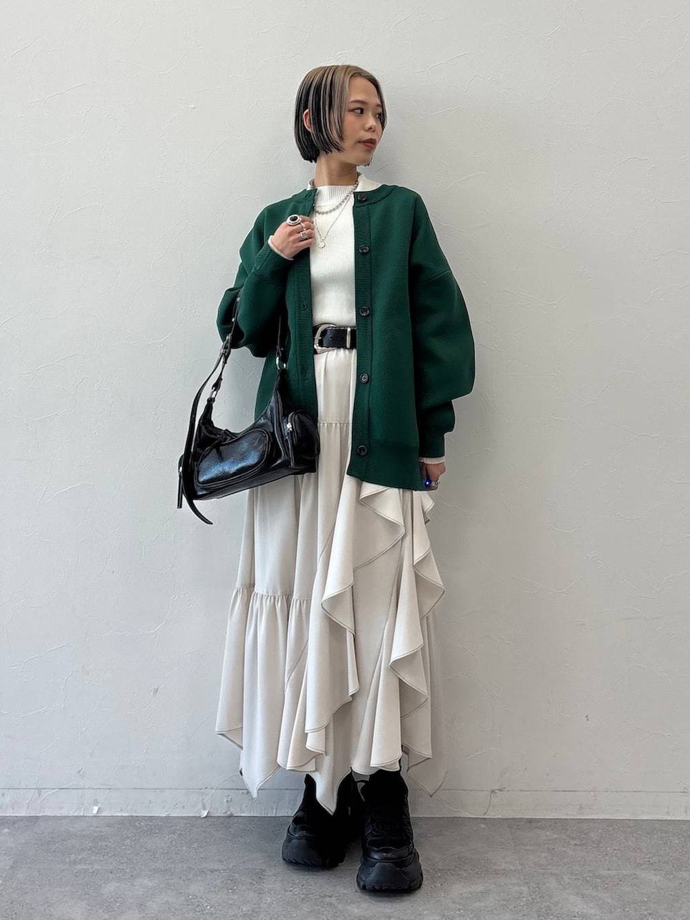 ブラック系のスニーカー、ブラック系のショルダーバッグ、ホワイト系のニット/セーターを着用したレディースの冬コーディネートの3枚目の写真