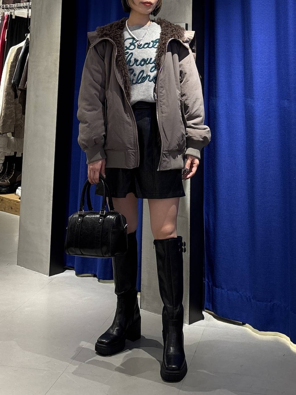 ブラック系のブーツ、ブラウン系のブルゾン、ブラック系のその他パンツを着用したレディースの冬コーディネートの2枚目の写真