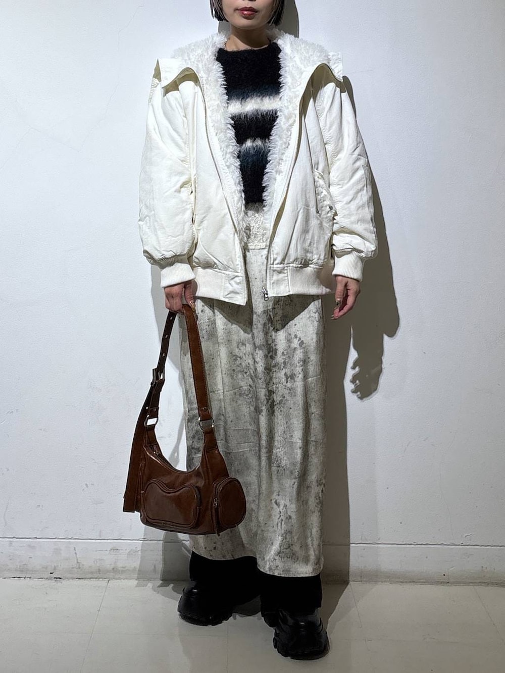 ブラック系のブーツ、ホワイト系のブルゾン、ブラウン系のショルダーバッグを着用したレディースの冬コーディネートの2枚目の写真