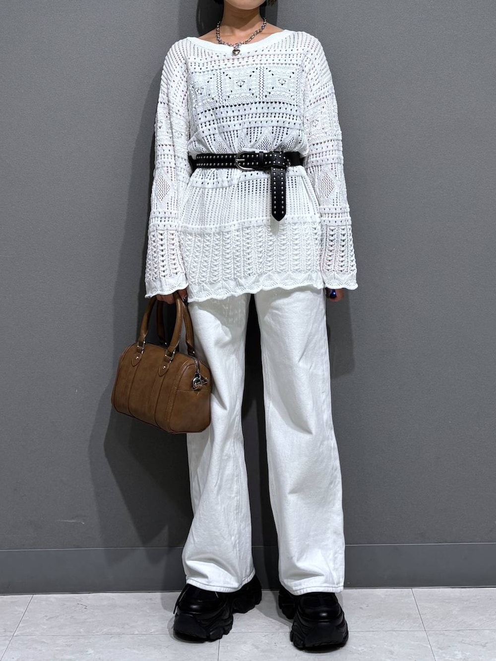 ブラック系のスニーカー、ホワイト系のスラックス、ブラウン系のボストンバッグを着用したレディースの春コーディネートの3枚目の写真