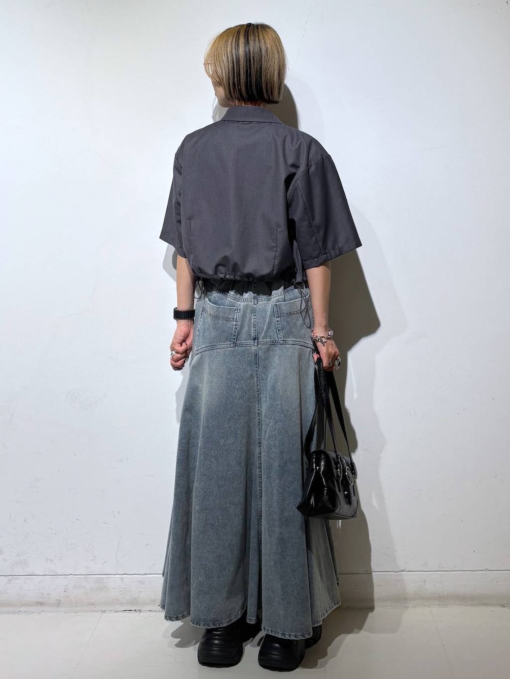ブラック系のスニーカー、ブルー系のデニムスカート、グレー系のTシャツ/カットソーを着用したレディースの夏コーディネートの5枚目の写真