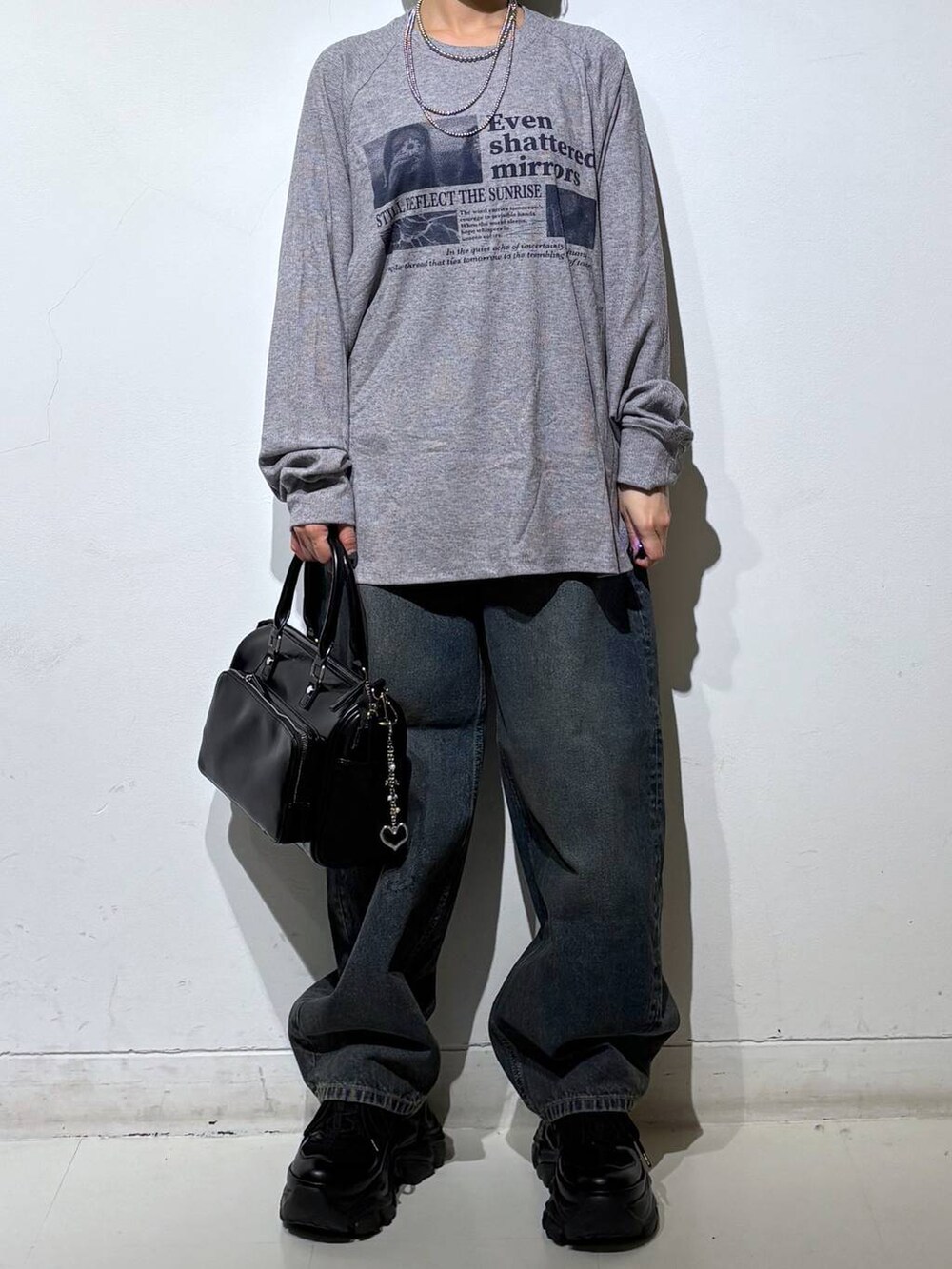 ブラック系のスニーカー、ブルー系のデニムパンツ、ブラック系のショルダーバッグを着用したレディースの春コーディネートの3枚目の写真