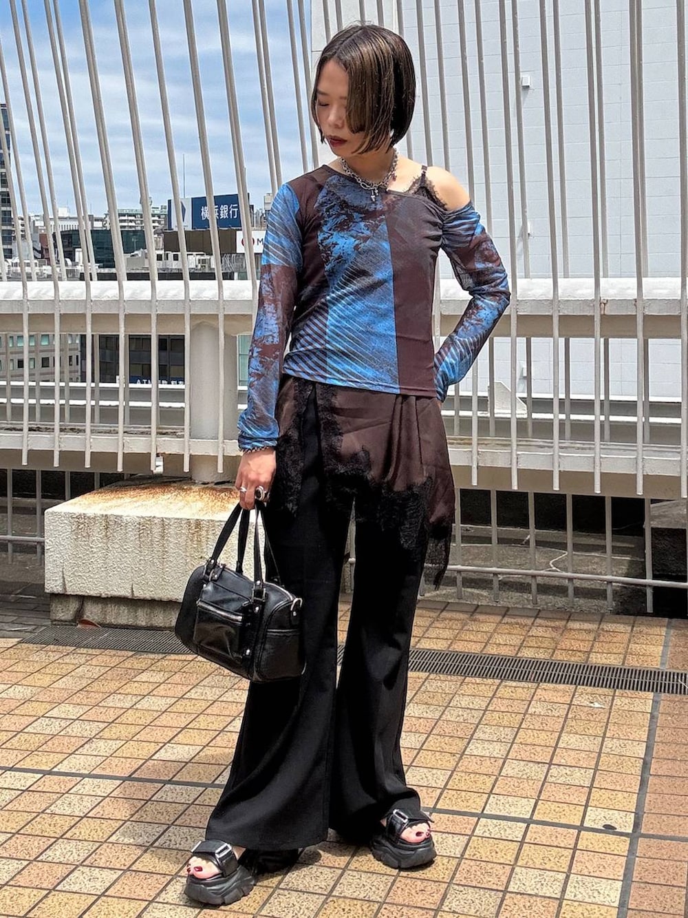 ブラック系のショルダーバッグ、ブラウン系のチュニック、ブラック系のスラックスを着用したレディースの夏コーディネートの5枚目の写真