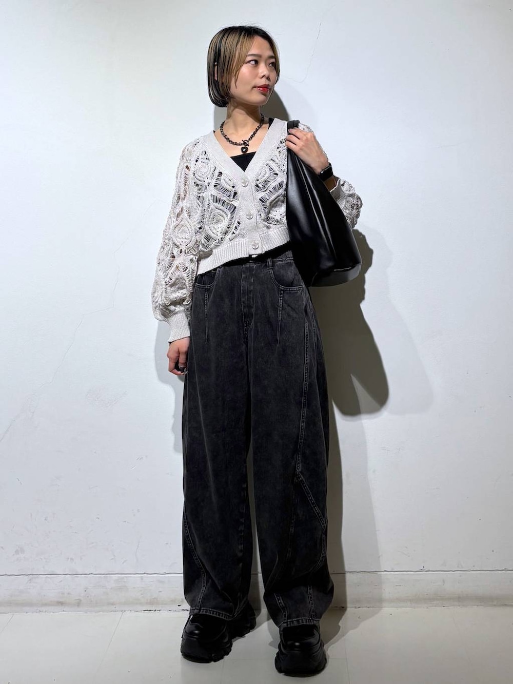 ブラック系のスニーカー、ベージュ系のカーディガン/ボレロ、ブラック系のデニムパンツを着用したレディースの春コーディネートの2枚目の写真