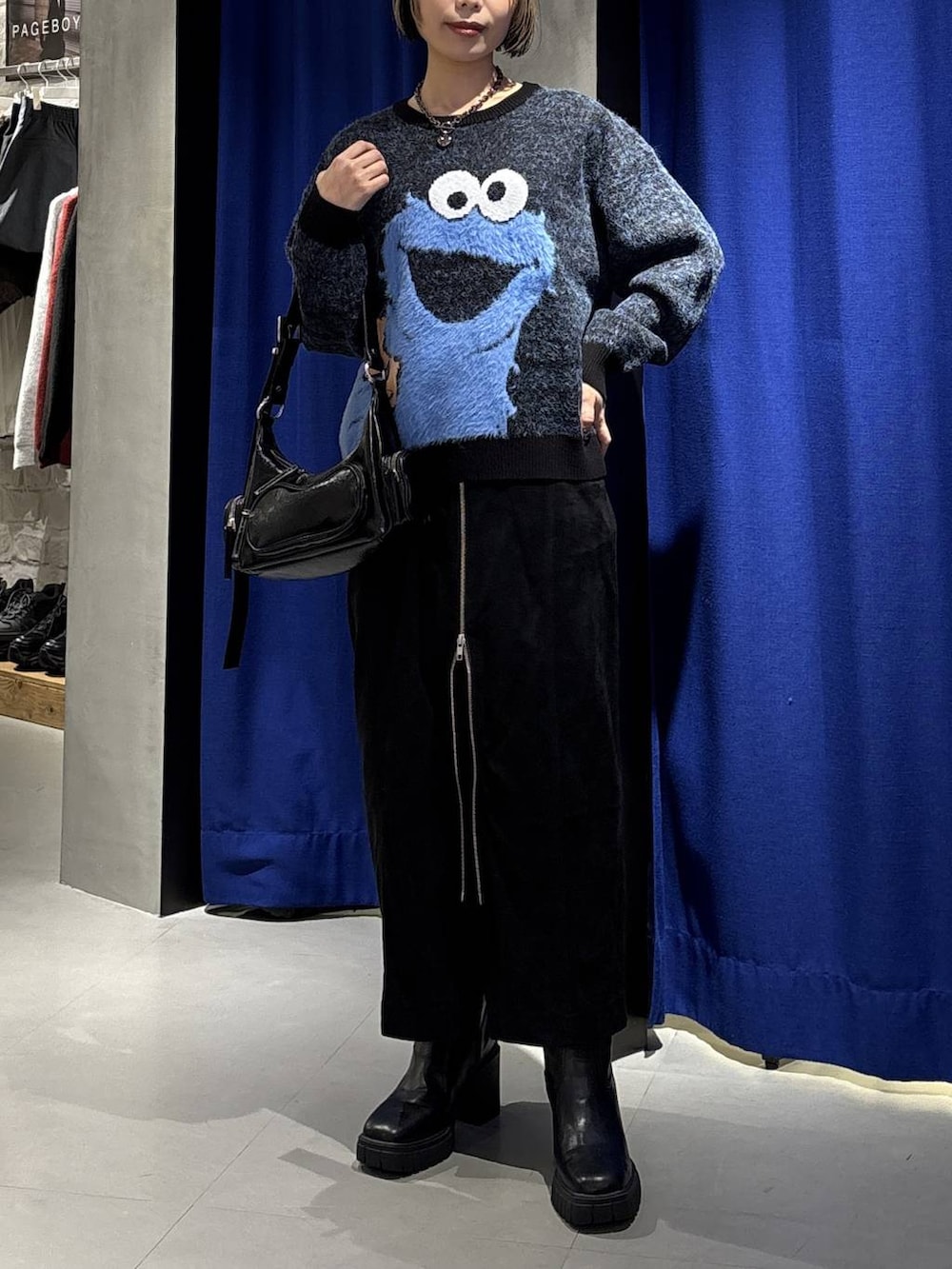 ブラック系のブーツ、ブラック系のショルダーバッグ、ブラック系のスカートを着用したレディースの冬コーディネートの2枚目の写真