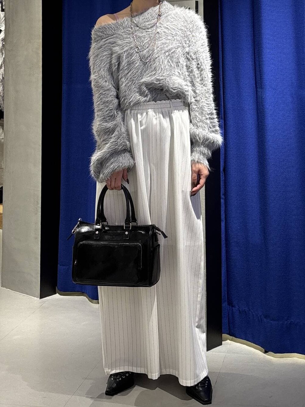 グレー系のニット/セーター、ブラック系のショルダーバッグ、ブラック系のサンダルを着用したレディースの冬コーディネートの2枚目の写真