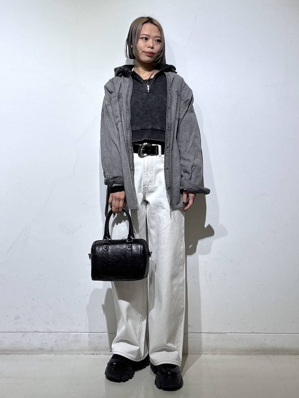 ブラック系のブーツ、ブラック系のTシャツ/カットソー、ホワイト系のスラックスを着用したレディースの冬コーディネートの2枚目の写真