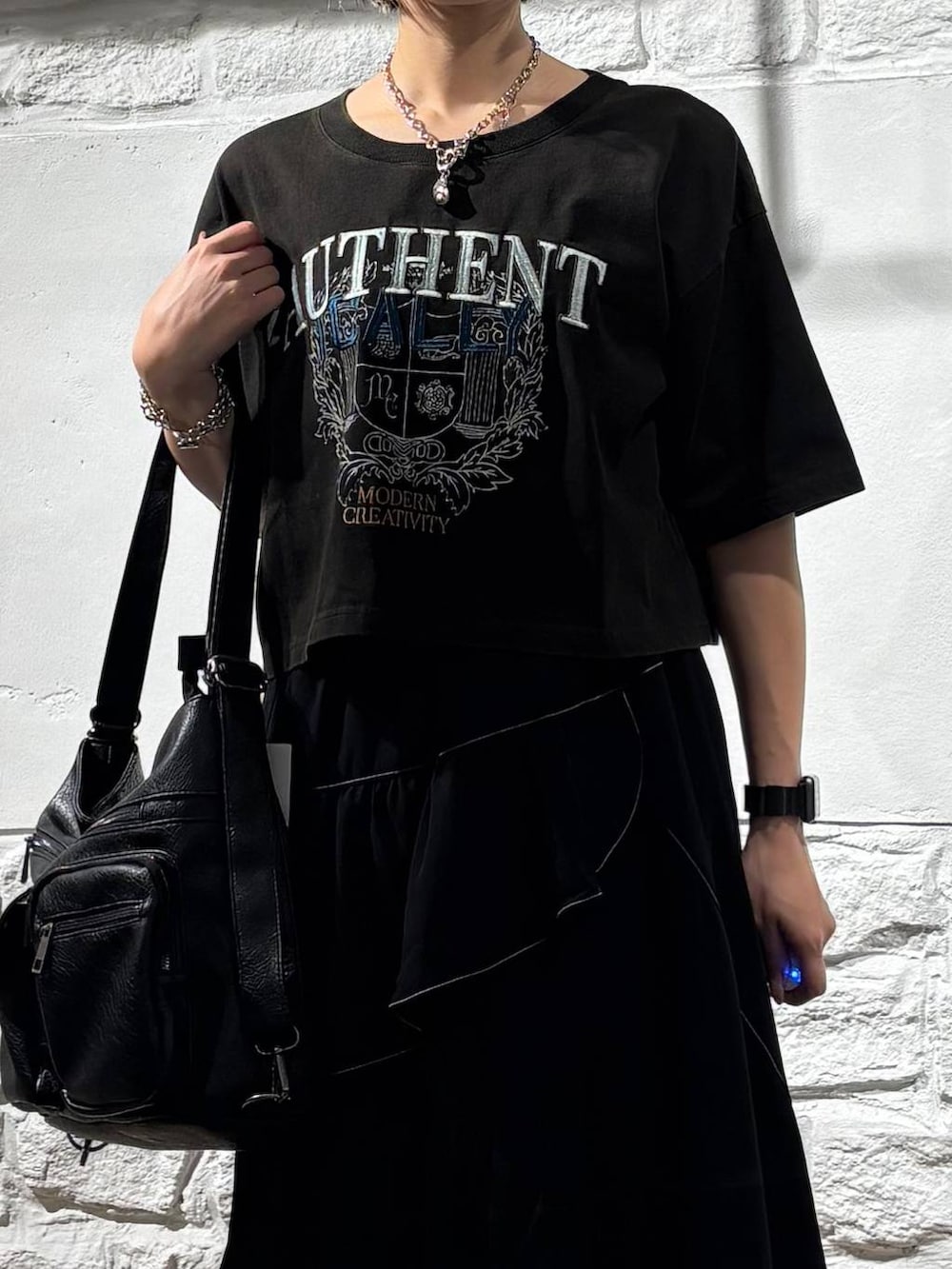 ブラック系のスカート、グレー系のTシャツ/カットソー、ブラック系のショルダーバッグを着用したレディースの夏コーディネートの4枚目の写真