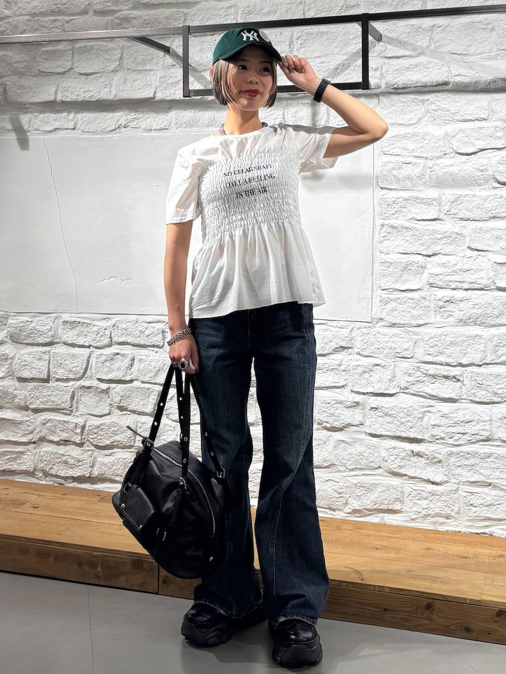 ブラック系のスニーカー、ブルー系のデニムパンツ、ブラック系のボストンバッグを着用したレディースの春コーディネートの2枚目の写真