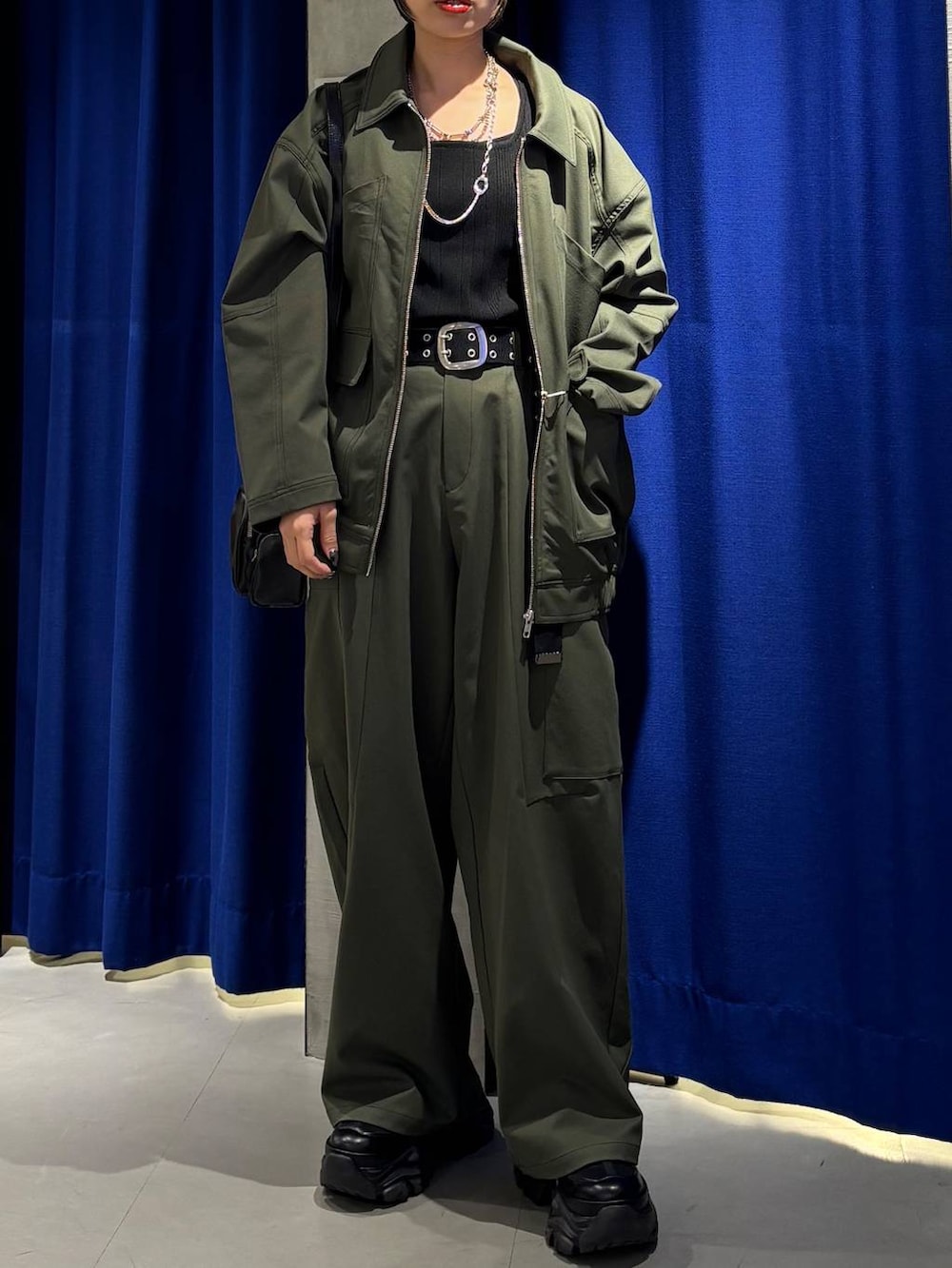 ブラック系のスニーカー、ブラック系のタンクトップ、グリーン系のカーゴパンツを着用したレディースの春コーディネートの4枚目の写真