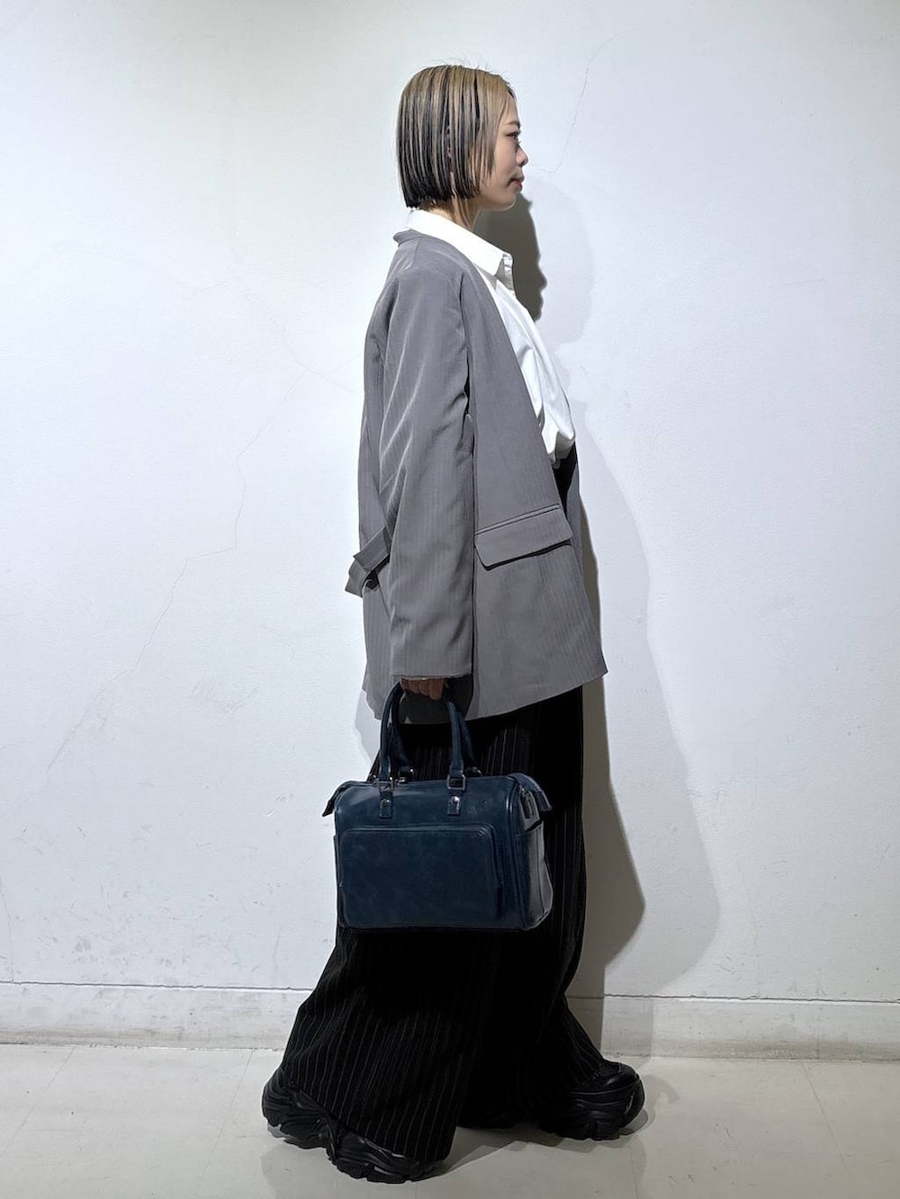 ブラック系のスニーカー、グレー系のテーラードジャケット、ブルー系のショルダーバッグを着用したレディースの冬コーディネートの3枚目の写真